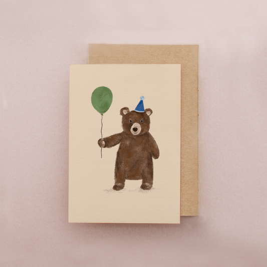 Card with a bear holding a green balloon and a blue party hat on a beige background